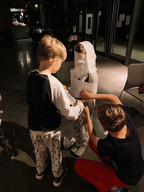 Dzieci zawijają się papierem, robiąc z siebie Mumię