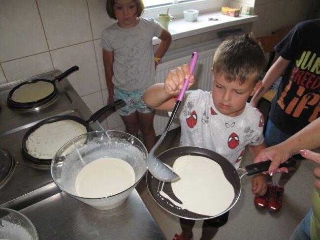 chłopiec nalewa ciasto na patelnię