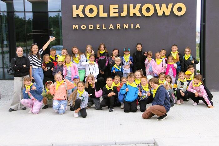 Dzieci pozują do zdjęcia przed wejściem do Kolejkowa