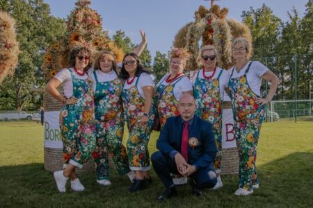 Pracownicy B+CK oraz dyrektor pozują do zdjęcia na tle wieńców dożynkowych